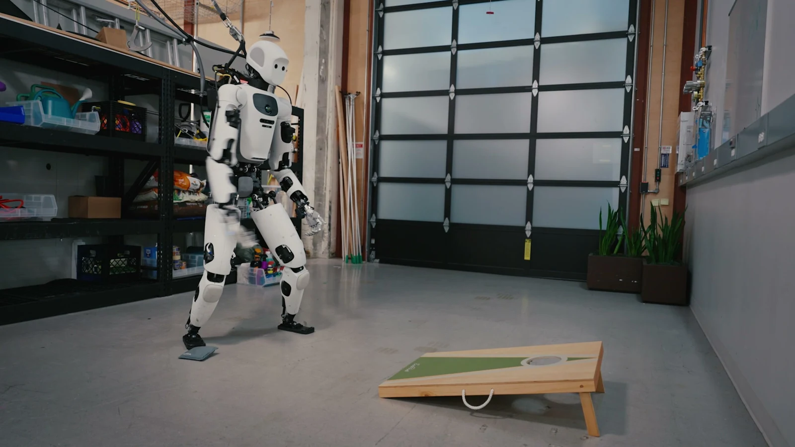 Le robot humanoïde Apollo face à une planche de cornhole dans un atelier, capture de la démonstration Google.